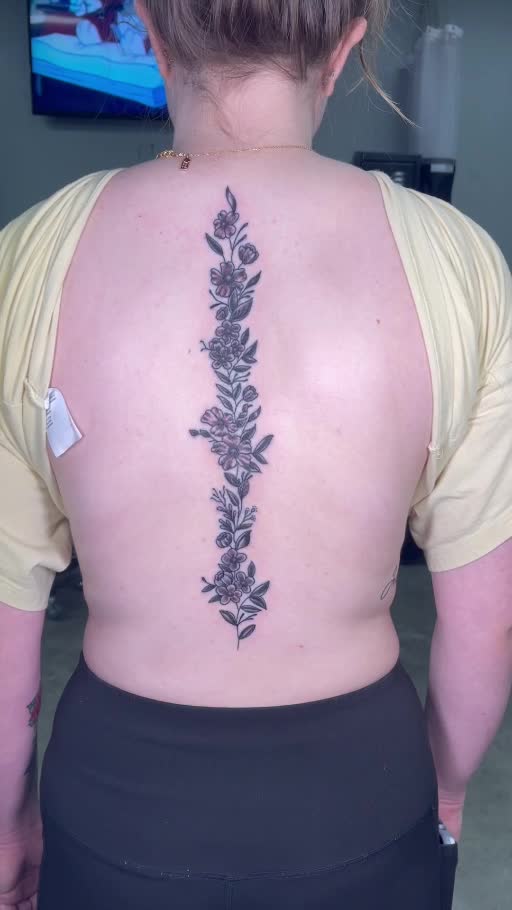 Fine-line floral spine tattoo
